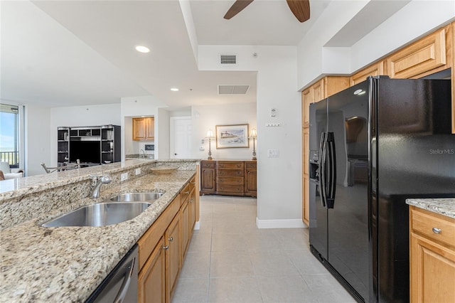 kitchen with black fridge, light stone countertops, and sink