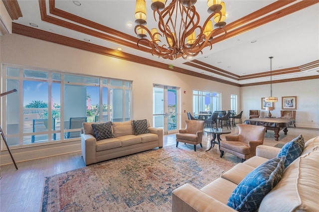 living room featuring ornamental molding, a tray ceiling, hardwood / wood-style floors, and a notable chandelier