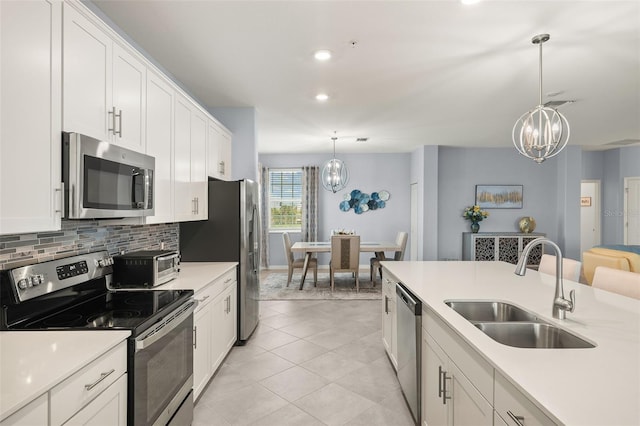 kitchen with hanging light fixtures, white cabinetry, appliances with stainless steel finishes, and sink