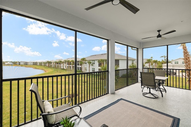 sunroom with ceiling fan and a water view