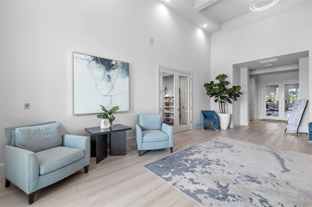 living area with light wood-type flooring, french doors, and a high ceiling