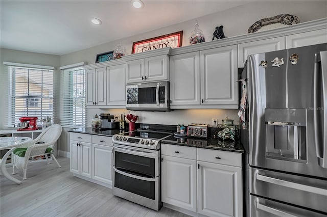 kitchen with white cabinets, stainless steel appliances, and light wood-type flooring