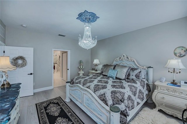 bedroom with light wood-type flooring and an inviting chandelier