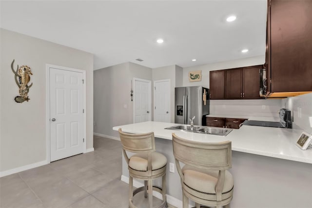 kitchen with sink, stainless steel fridge, a kitchen breakfast bar, range, and kitchen peninsula