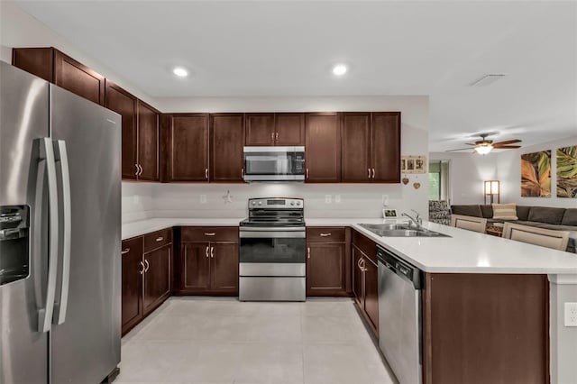 kitchen featuring appliances with stainless steel finishes, sink, ceiling fan, kitchen peninsula, and dark brown cabinets