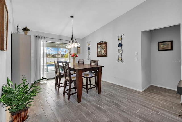 dining area featuring a chandelier, hardwood / wood-style floors, and lofted ceiling