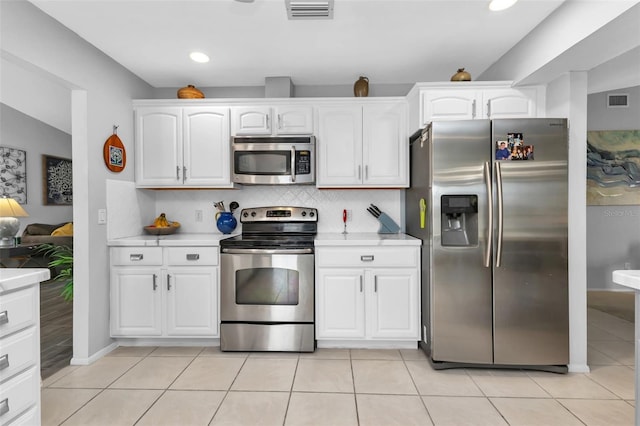 kitchen featuring light tile patterned flooring, backsplash, white cabinetry, and appliances with stainless steel finishes