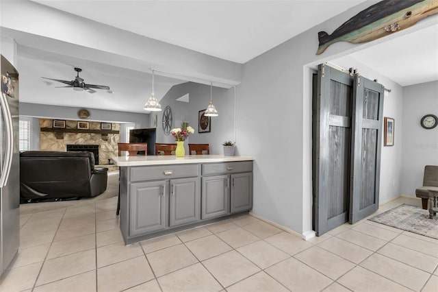 kitchen featuring kitchen peninsula, pendant lighting, ceiling fan, gray cabinetry, and a barn door