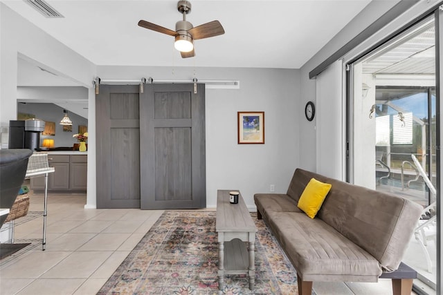 tiled living room with ceiling fan and a barn door