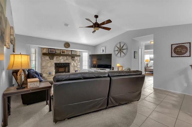 living room featuring vaulted ceiling, a stone fireplace, a healthy amount of sunlight, and light tile patterned floors