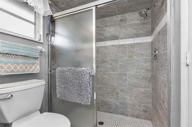 bathroom featuring toilet and a shower with shower door