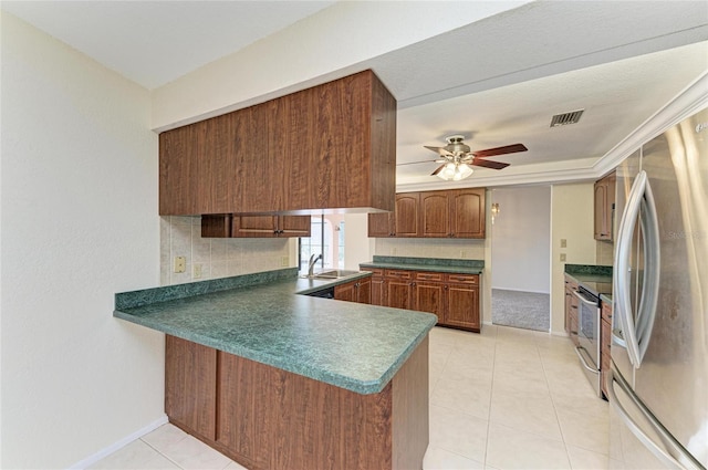 kitchen with light tile patterned flooring, appliances with stainless steel finishes, sink, decorative backsplash, and kitchen peninsula