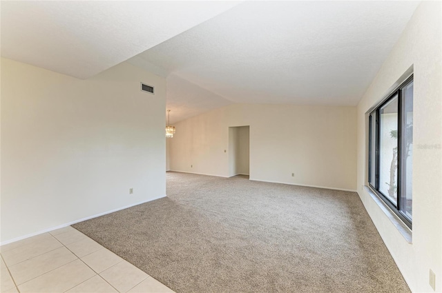 empty room with lofted ceiling, light colored carpet, and an inviting chandelier