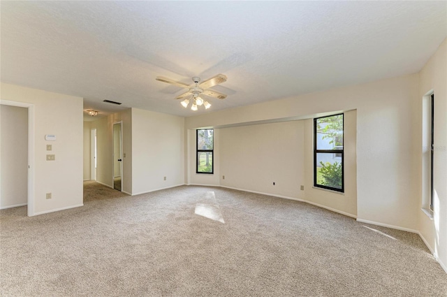 carpeted spare room with ceiling fan, plenty of natural light, and a textured ceiling