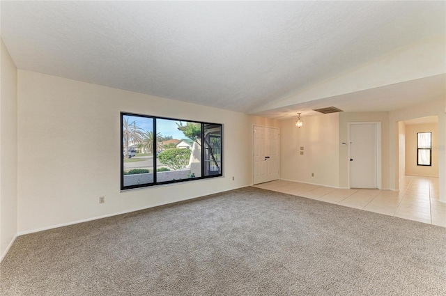 unfurnished room with vaulted ceiling, baseboards, light carpet, and light tile patterned floors