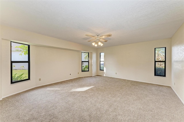unfurnished room with a textured ceiling, carpet flooring, baseboards, and ceiling fan