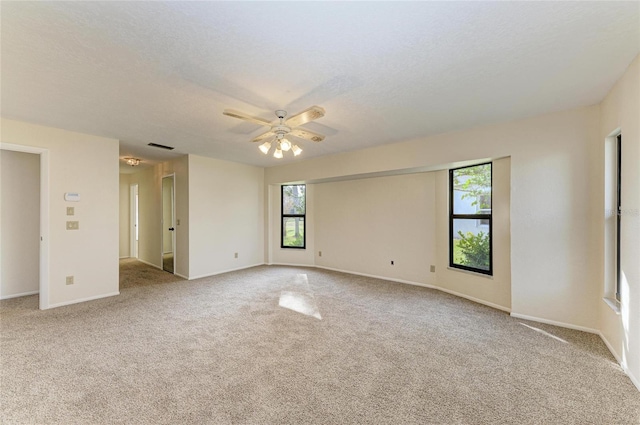 carpeted spare room featuring plenty of natural light, a ceiling fan, and baseboards