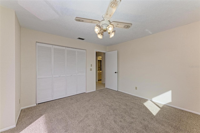 unfurnished bedroom featuring carpet, visible vents, a closet, baseboards, and ceiling fan