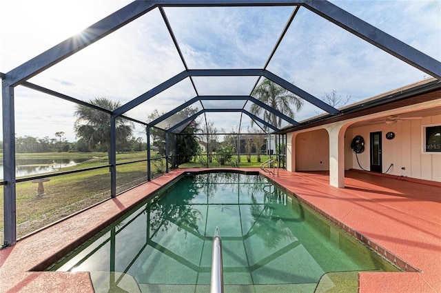 pool with glass enclosure, a water view, a ceiling fan, and a patio