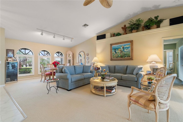 living room featuring vaulted ceiling, light colored carpet, track lighting, and ceiling fan