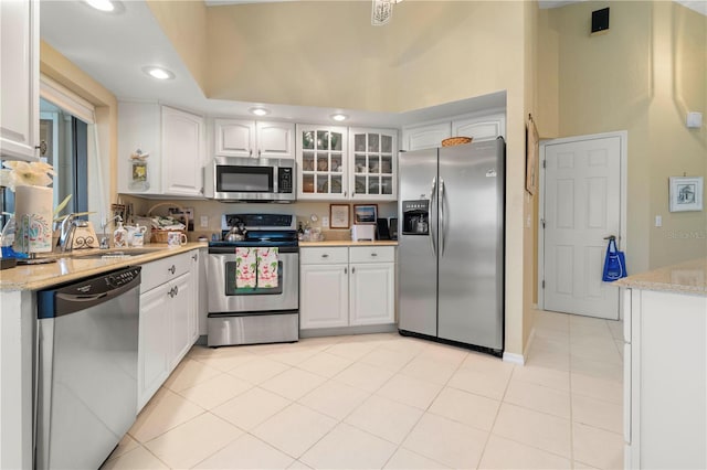 kitchen featuring sink, light tile patterned floors, white cabinetry, stainless steel appliances, and light stone countertops