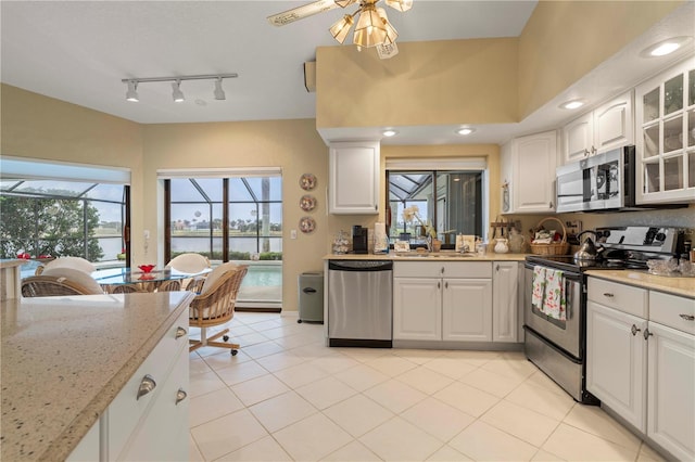 kitchen with white cabinetry, stainless steel appliances, light stone countertops, and sink