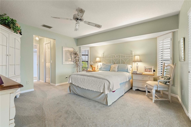 bedroom featuring light carpet, a textured ceiling, and ceiling fan