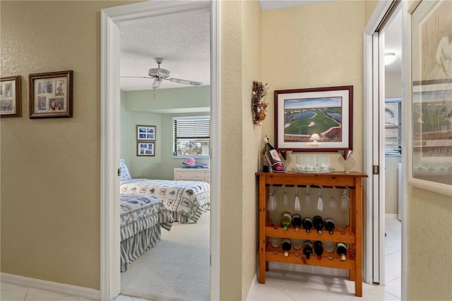 corridor with a textured ceiling and light tile patterned floors