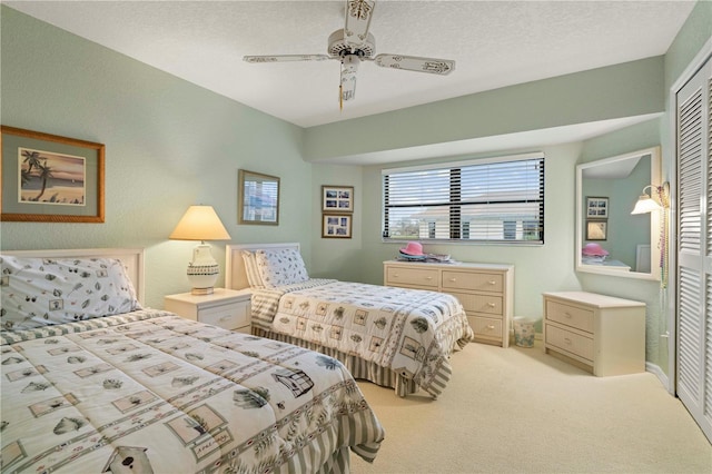 carpeted bedroom featuring a textured ceiling, ceiling fan, and a closet