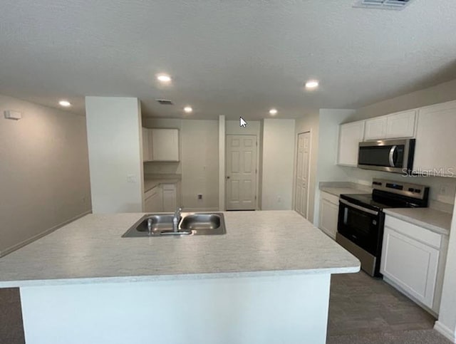 kitchen featuring appliances with stainless steel finishes, a kitchen island with sink, sink, and white cabinets