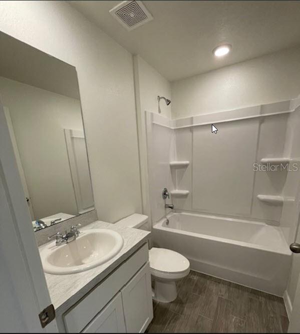 full bathroom featuring vanity, hardwood / wood-style flooring, shower / washtub combination, and toilet