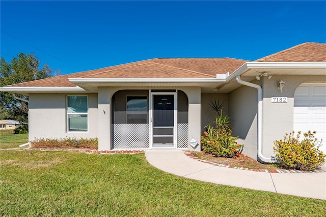 entrance to property featuring a garage and a lawn