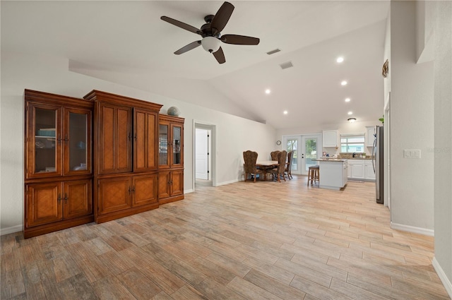 unfurnished living room with light hardwood / wood-style flooring, ceiling fan, and vaulted ceiling