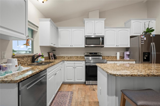 kitchen featuring stainless steel appliances, white cabinetry, lofted ceiling, and sink