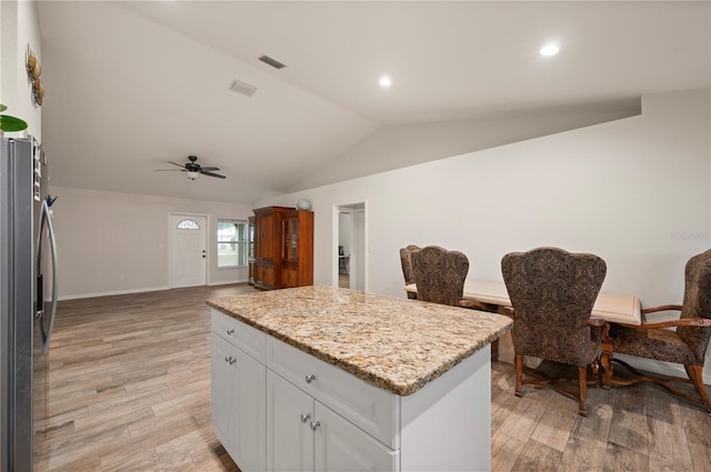 kitchen with a kitchen island, white cabinetry, light hardwood / wood-style floors, stainless steel fridge with ice dispenser, and light stone countertops