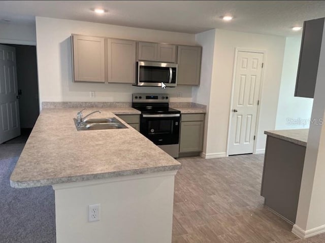 kitchen featuring sink, gray cabinetry, light hardwood / wood-style floors, kitchen peninsula, and stainless steel appliances