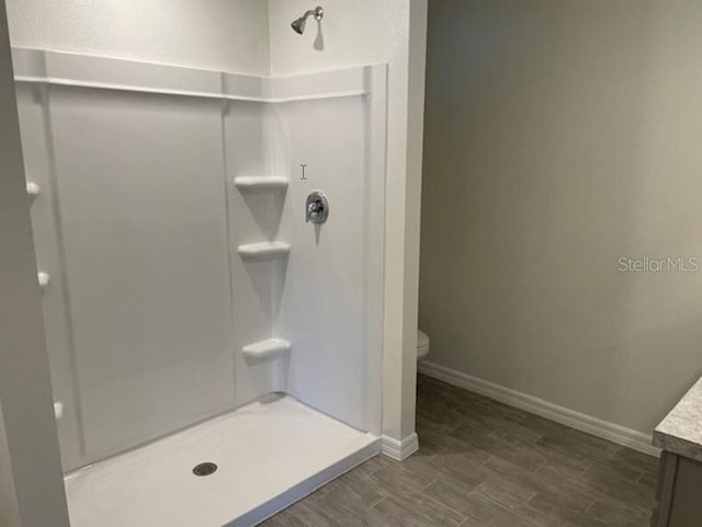 bathroom featuring hardwood / wood-style flooring, toilet, vanity, and walk in shower