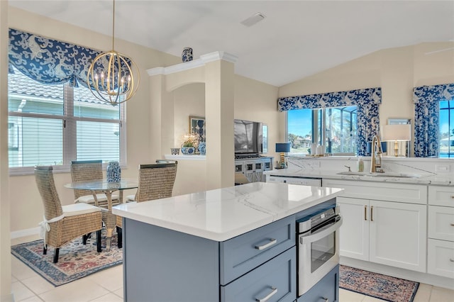 kitchen with sink, decorative light fixtures, light tile patterned floors, light stone countertops, and white cabinets