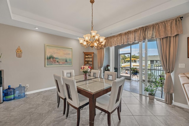 tiled dining room featuring a tray ceiling and an inviting chandelier