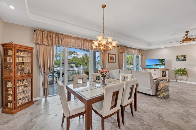 dining space with ceiling fan with notable chandelier and a raised ceiling