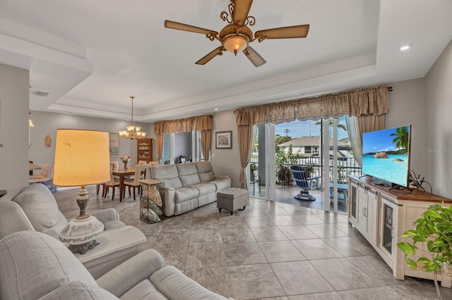 living room with ceiling fan with notable chandelier and a raised ceiling