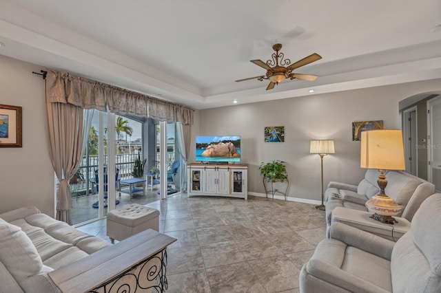 living room with a tray ceiling and ceiling fan