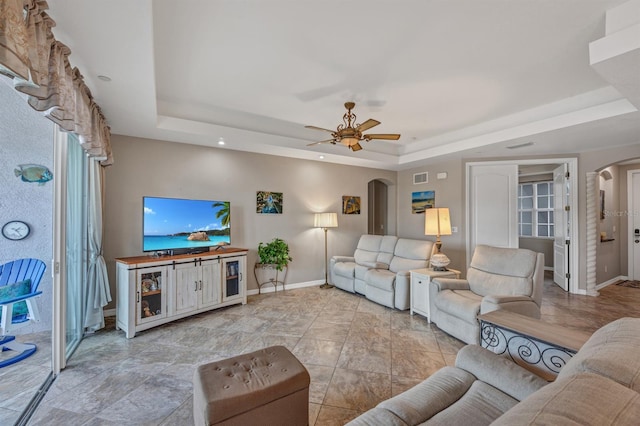 living room with ceiling fan and a tray ceiling