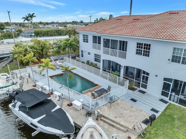 rear view of property featuring a fenced in pool, a water view, and a patio