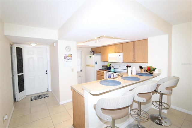 kitchen featuring light tile patterned flooring, white appliances, and kitchen peninsula