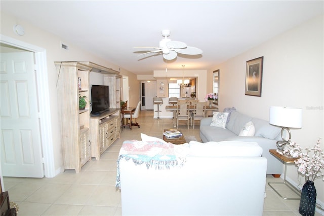 tiled living room featuring ceiling fan with notable chandelier