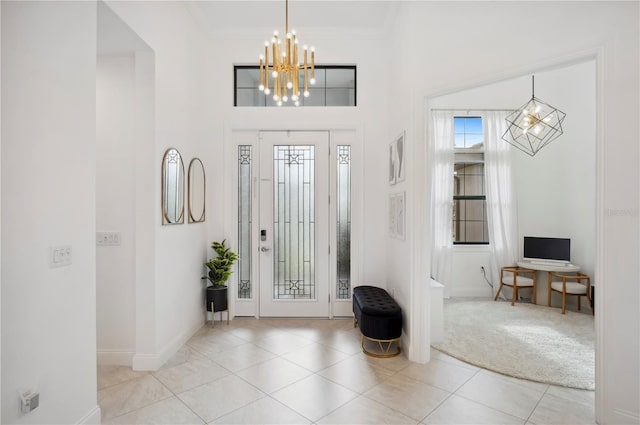 tiled foyer with a notable chandelier, a towering ceiling, and ornamental molding