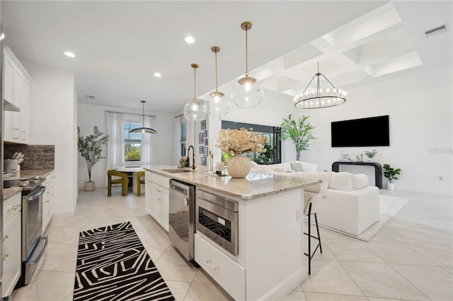 kitchen with white cabinets, appliances with stainless steel finishes, hanging light fixtures, a center island with sink, and coffered ceiling