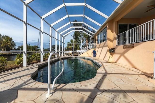 view of pool with a water view, a patio area, and glass enclosure