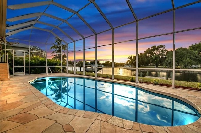 pool at dusk featuring a water view, glass enclosure, and a patio area